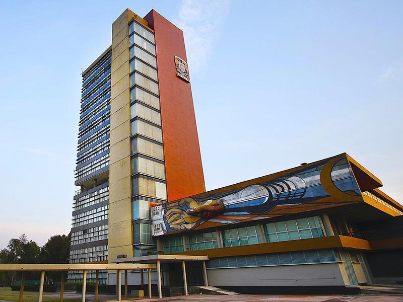 Vista de la Torre de Rectoría en campus central de la Universidad Nacional de México y el mural "Las fechas en la historia de México o el derecho a la cultura" de David Alfaro Siqueiros en muro norte.